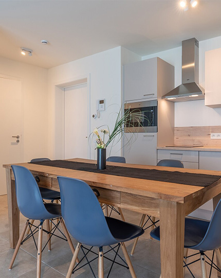 Eettafel met stoelen en open keuken in een assistentie woning van Gaudium in Mol