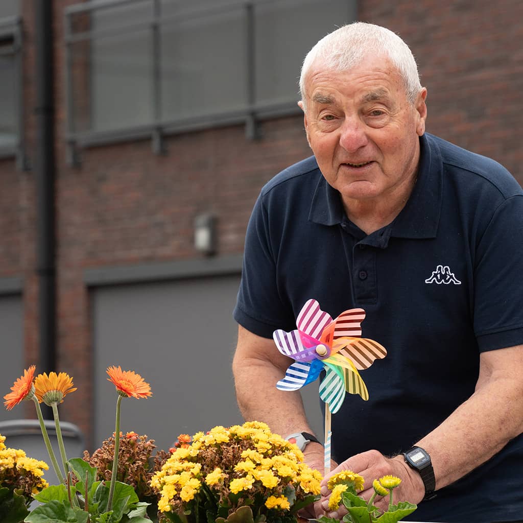 Bewoner vergzorgt de planten in de tuin van Gaudium assistentiewoningen in Mol