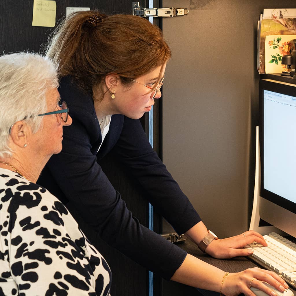 Zorgassistente helpt een bewoner met de computer bij Gaudium assistentiewoningen in Mol