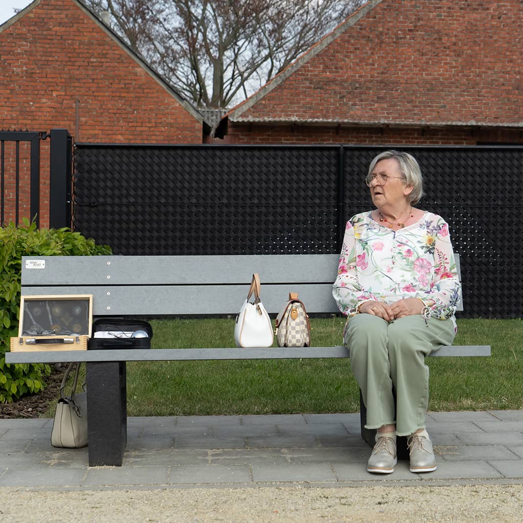 Bewoner zit op een bank in de tuin van Gaudium assistentiewoningen in Mol
