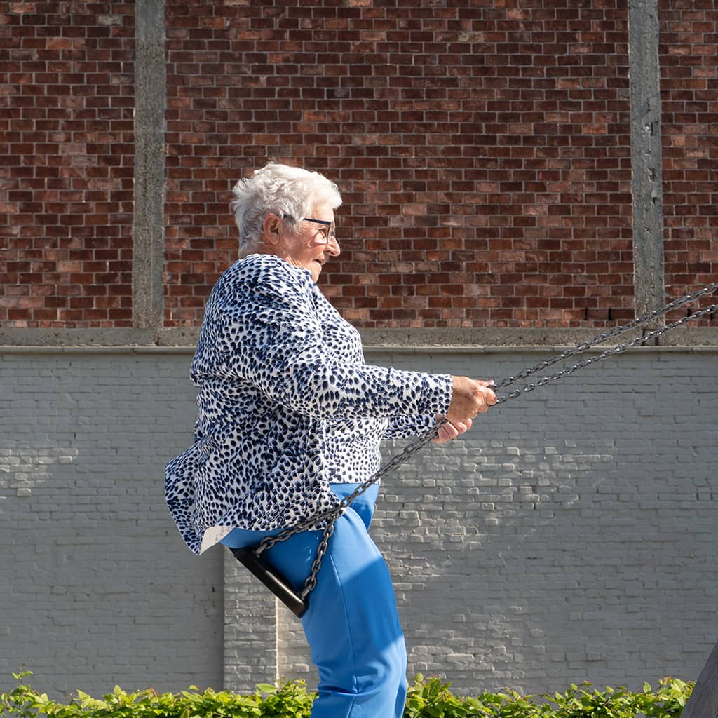 Bewoner schommelt in de speeltuin van Gaudium assistentiewoningen in Mol